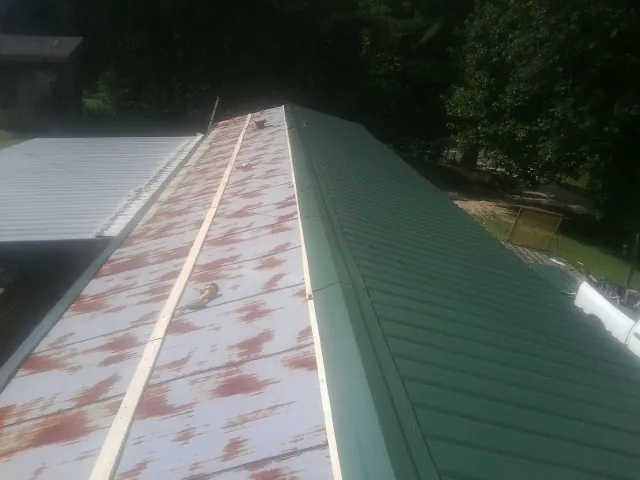 Old rusted panels beside newly installed green metal roofing — Wind Damage Roof Repair by Roofing Brothers in Elmore