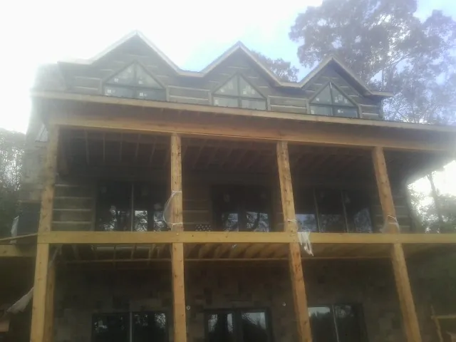 Dormers and porch framing on a large log home under construction — Roof Coating work by our crew in Elmore