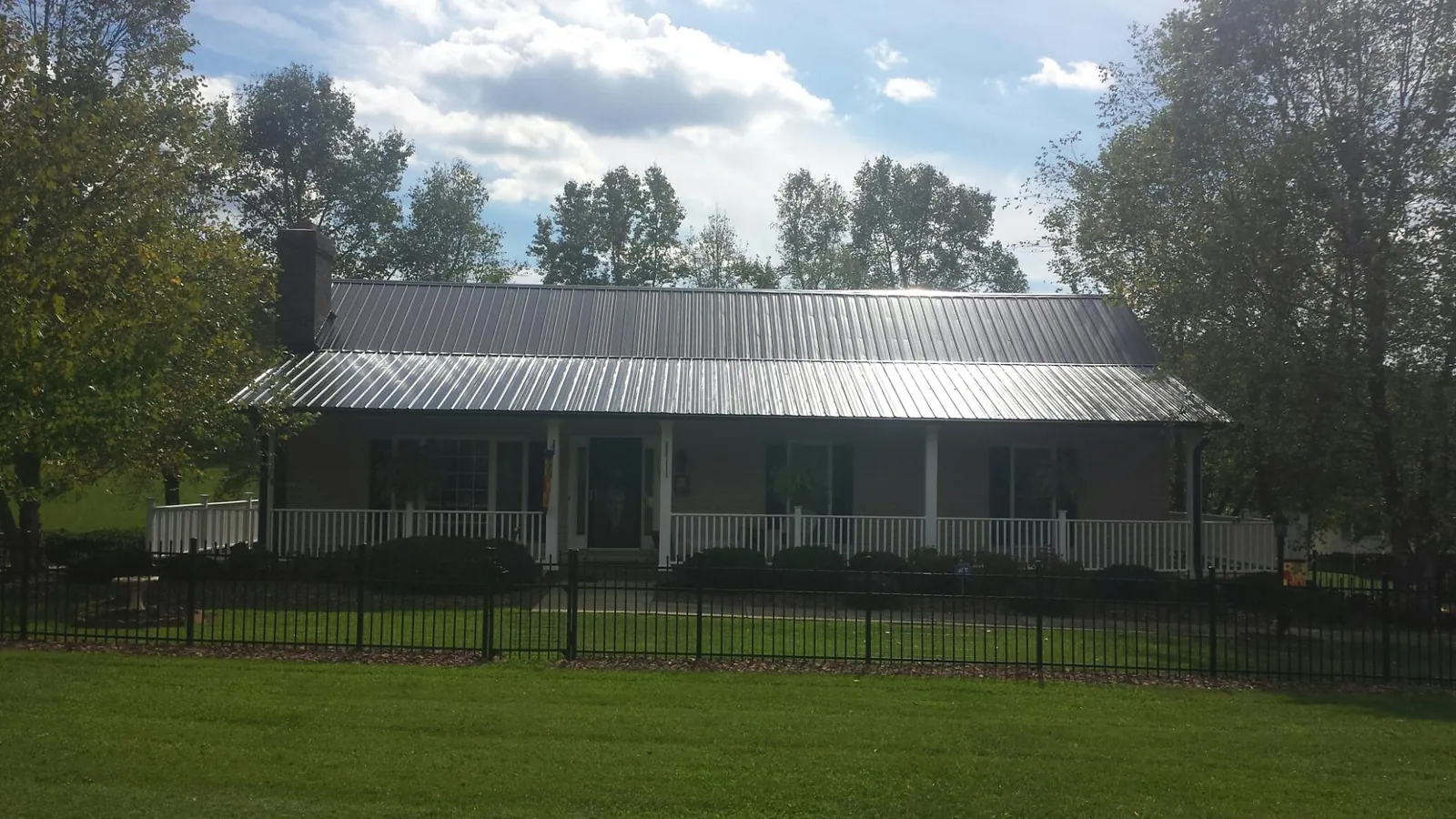 Gray metal roof on a brick ranch with a full width front porch — Gutter Guard Installation work by our crew in Elmore