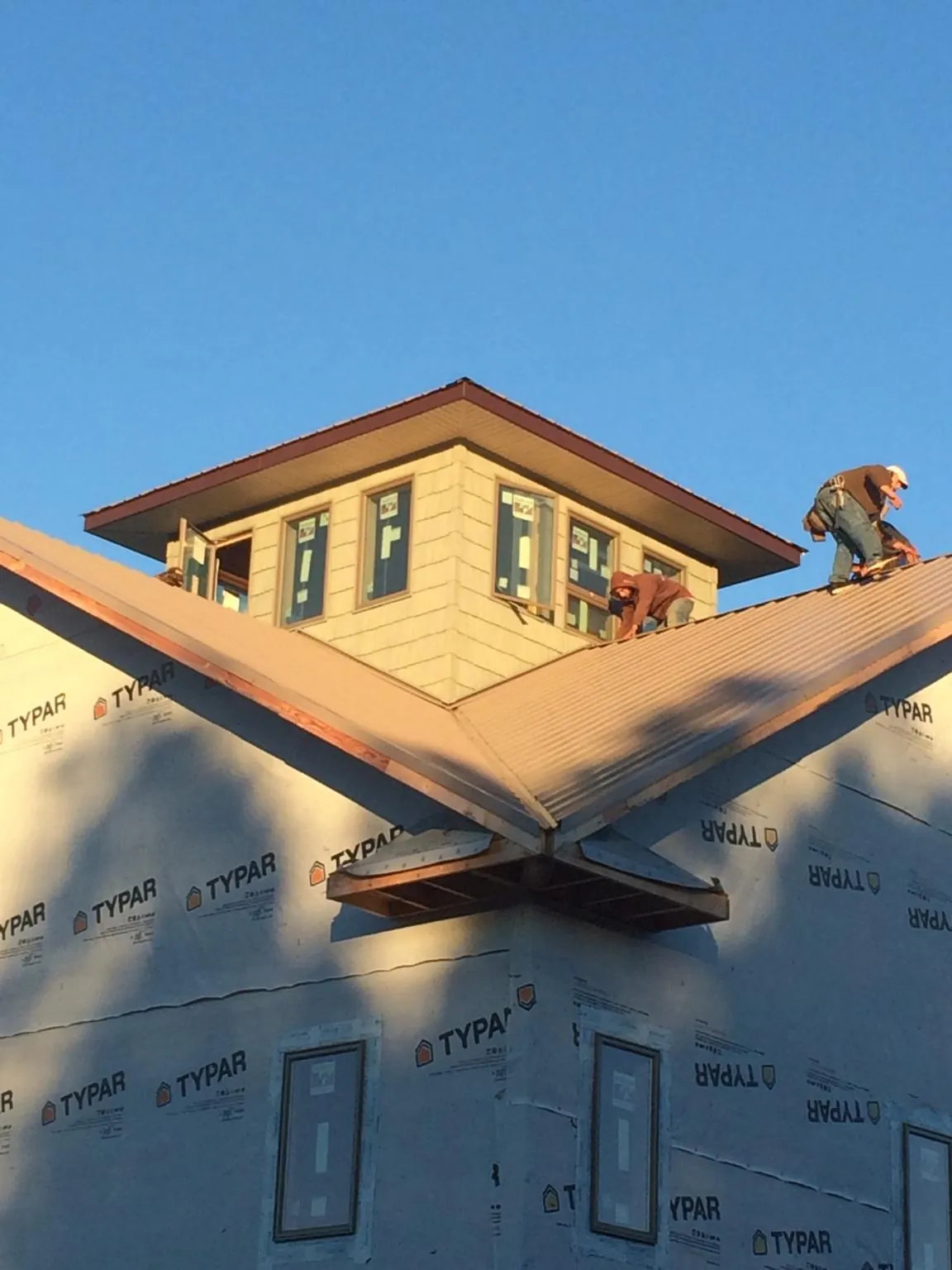 Roofers working around a rooftop cupola on a new metal roof at sunset — Roof Waterproofing in Elmore by Roofing Brothers